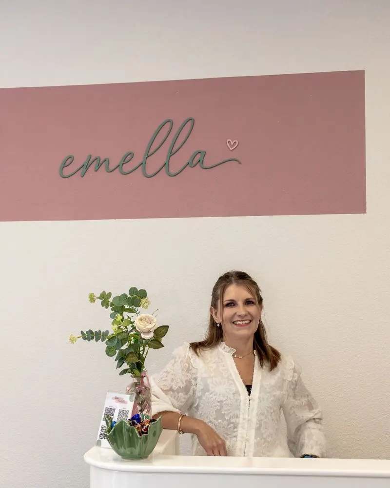Barbara Zeidler lächelnd an der Theke unter dem emella-Schriftzug