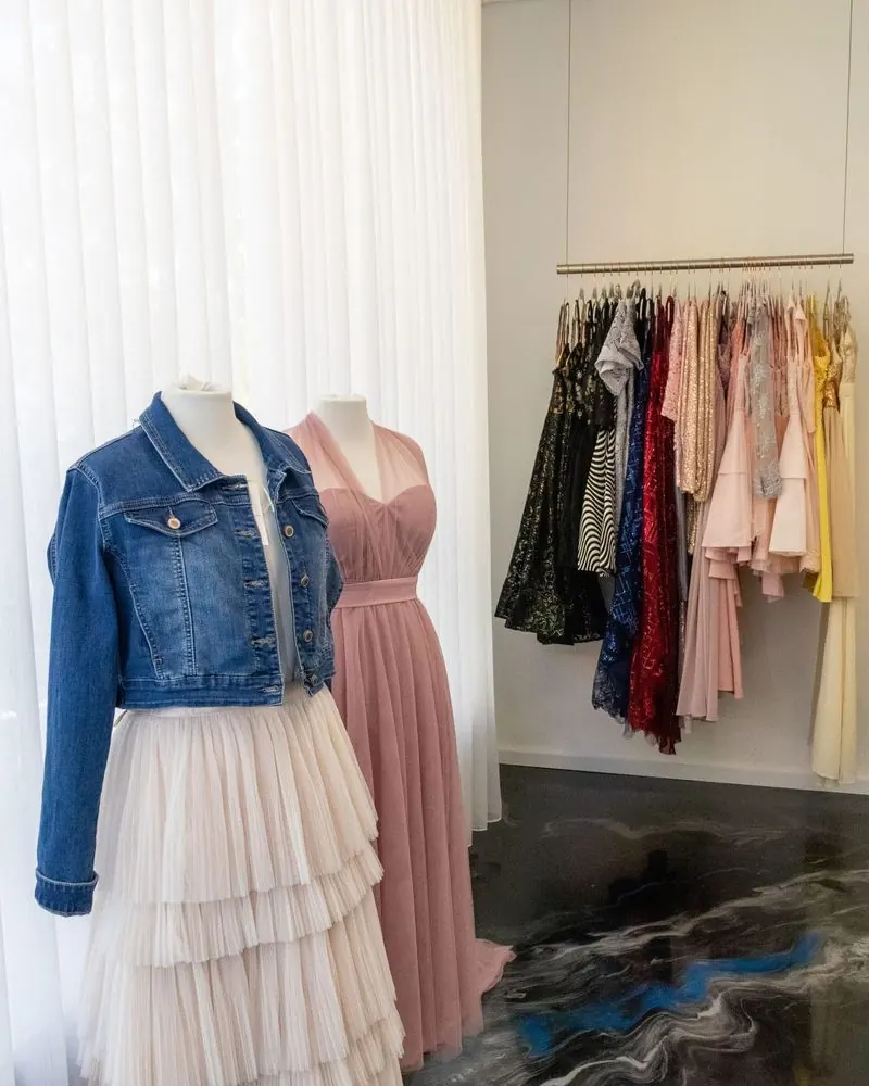 Tüllrock mit Jeansjacke und rosa Tüllkleid vor einer Stange mit bunten Festkleidern