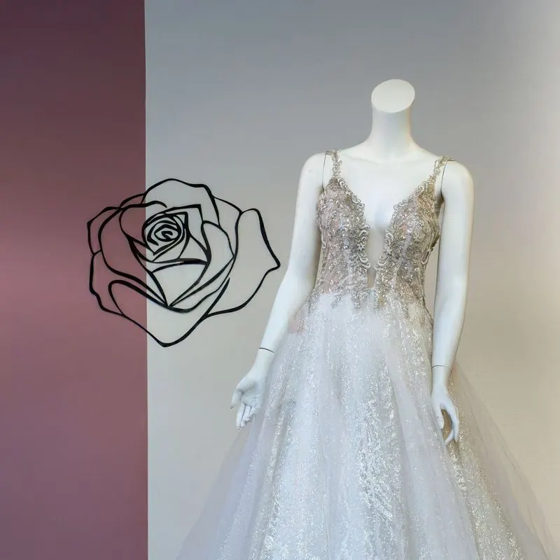 Brautkleid vor der rosa Wand mit Rosen-Motiv