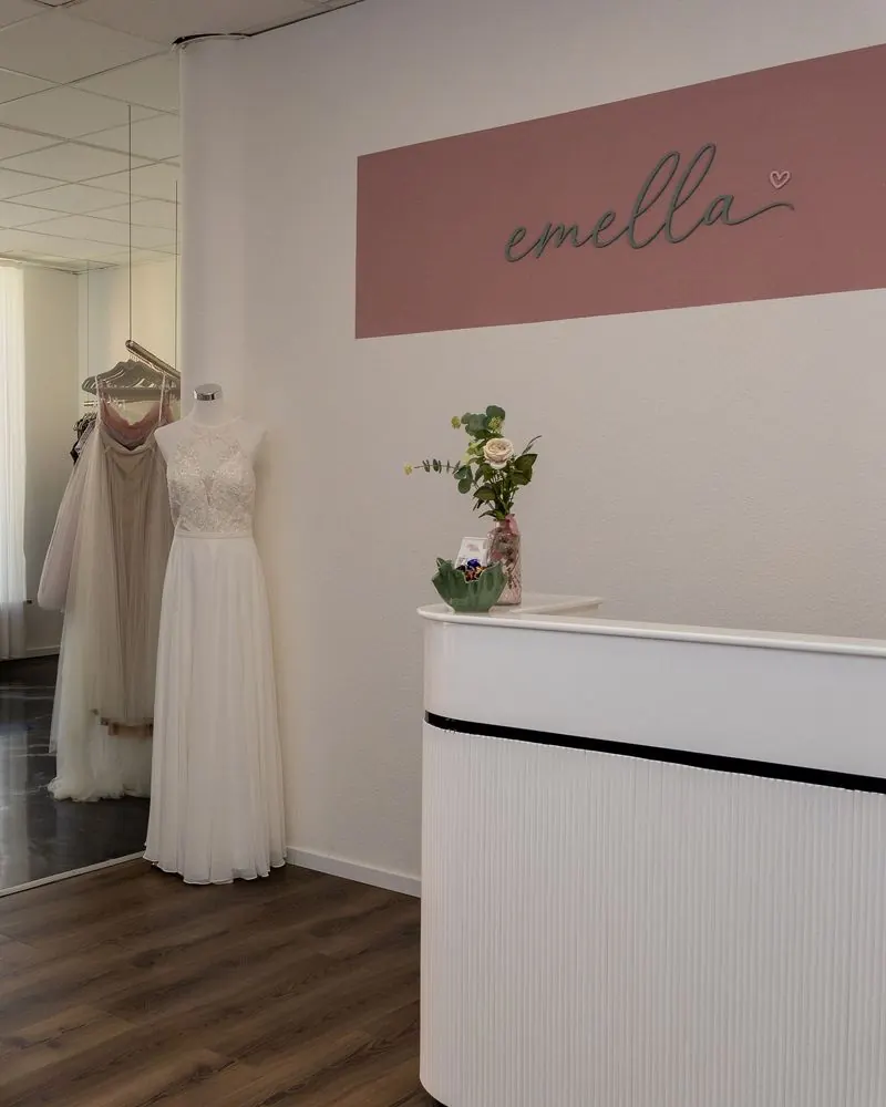 Eingangsbereich von emella mit Theke und rosa Logowand