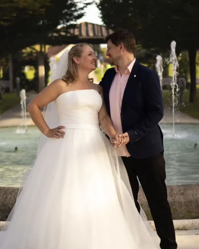 Braut im Tüllkleid mit ihrem Mann vor einem Brunnen