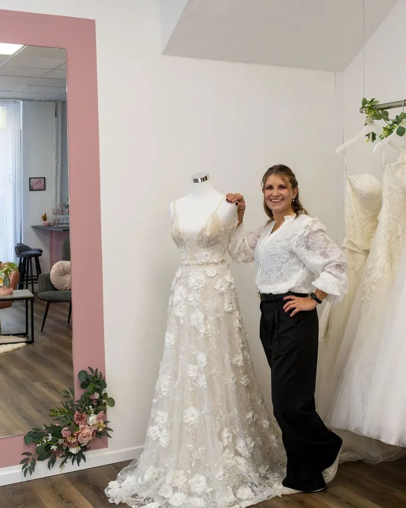 Barbara Zeidler, Inhaberin von emella Brautmode in Burgkunstadt, neben einem Brautkleid vor dem großen Spiegel